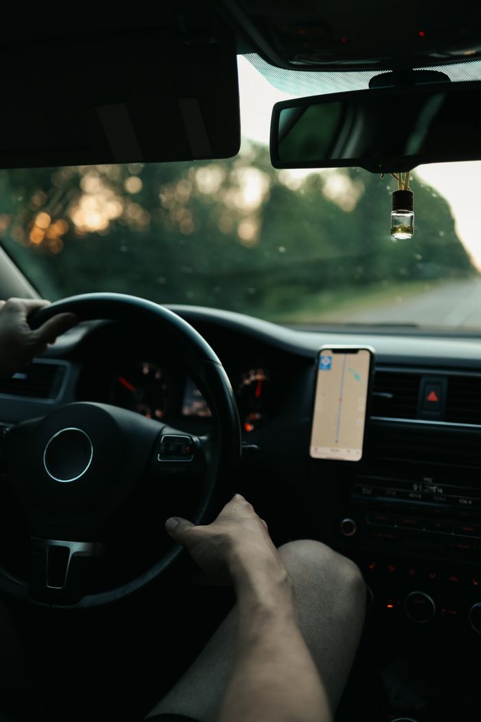 View from inside a car showing hands on the wheel, driving with a GPS-guided journey.